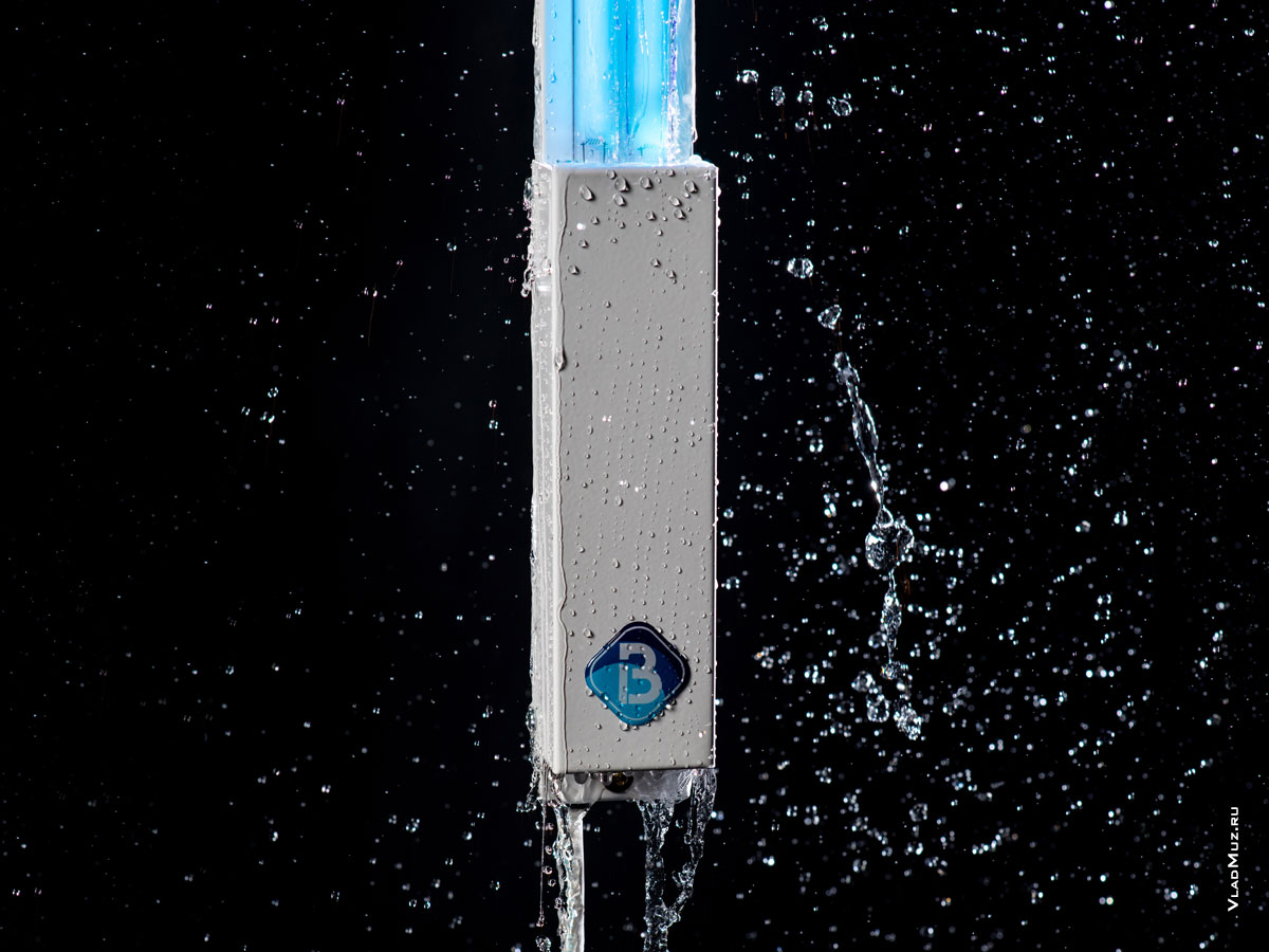 Фото корпуса бактерицидного УФ-облучателя Bact Ray с текущими по нему струями воды и летящими каплями и струями в воздухе