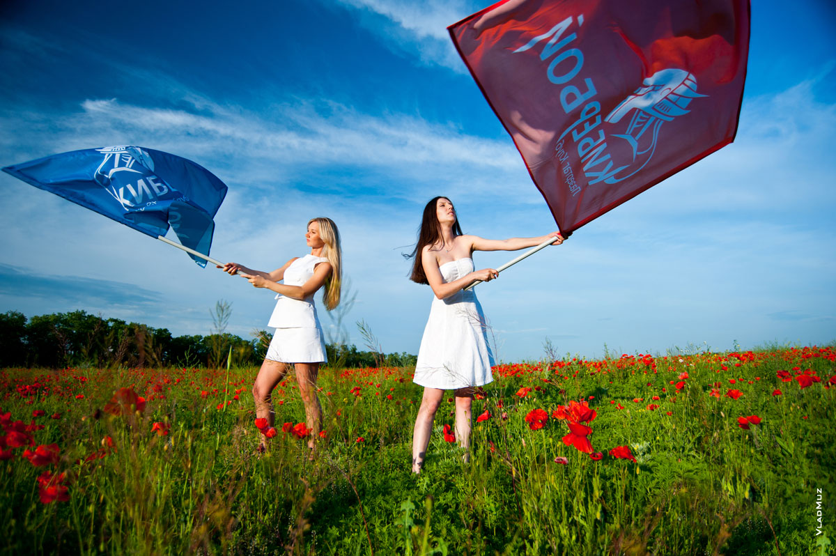 Фото двух девушек в белом на фоне синего неба с красным и синим флагами «Кибербой»
