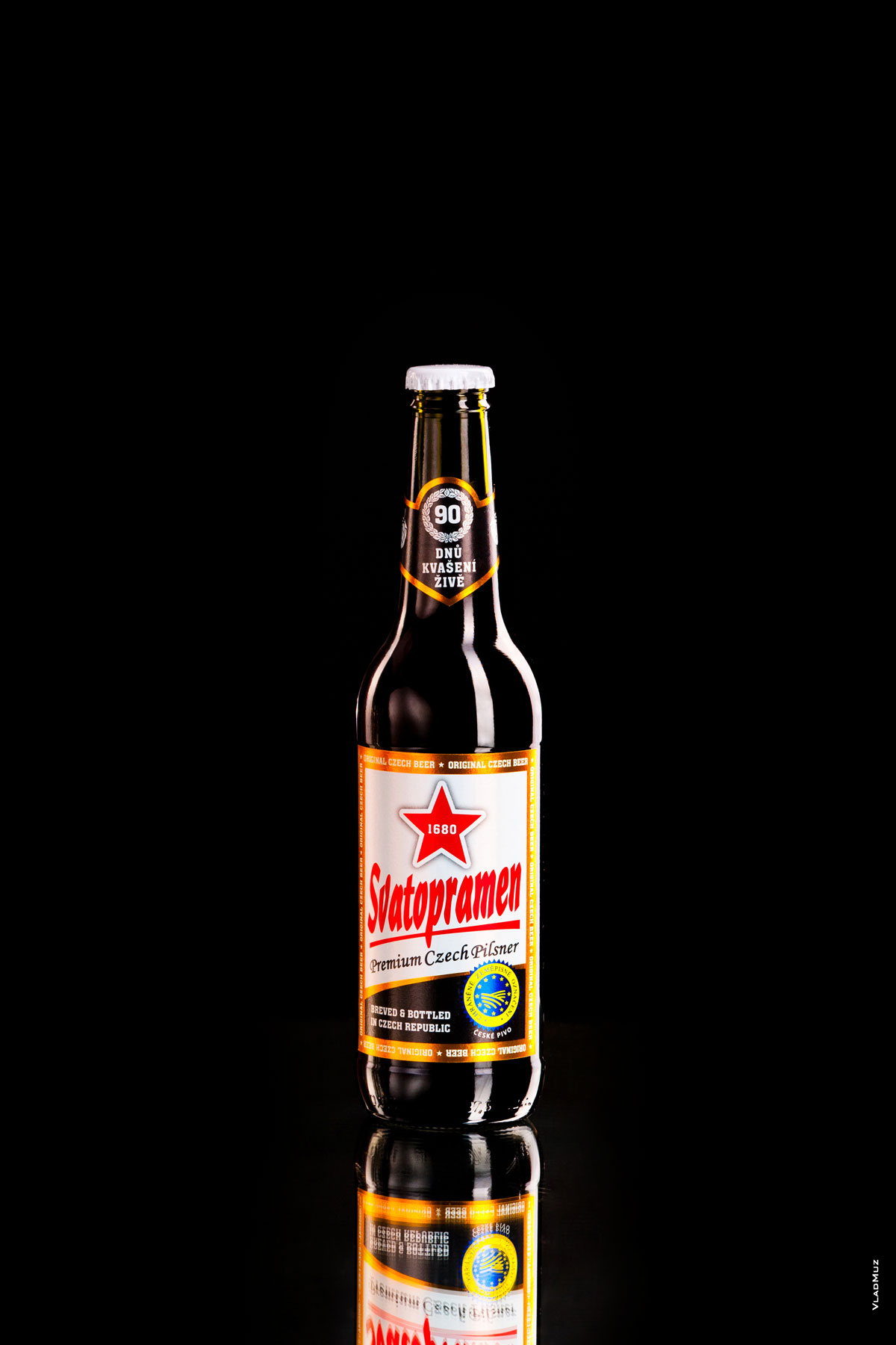 Рекламная фотография бутылки темного пива «Святопрамен» на черном фоне с бликами