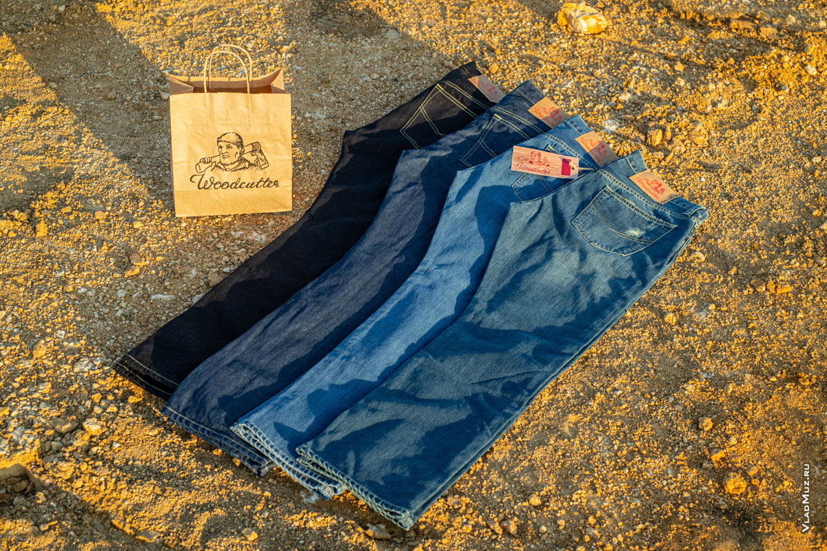 Фото джинсовых брюк и бумажного пакета с логотипом Woodcutter на фоне желтого грунта карьера