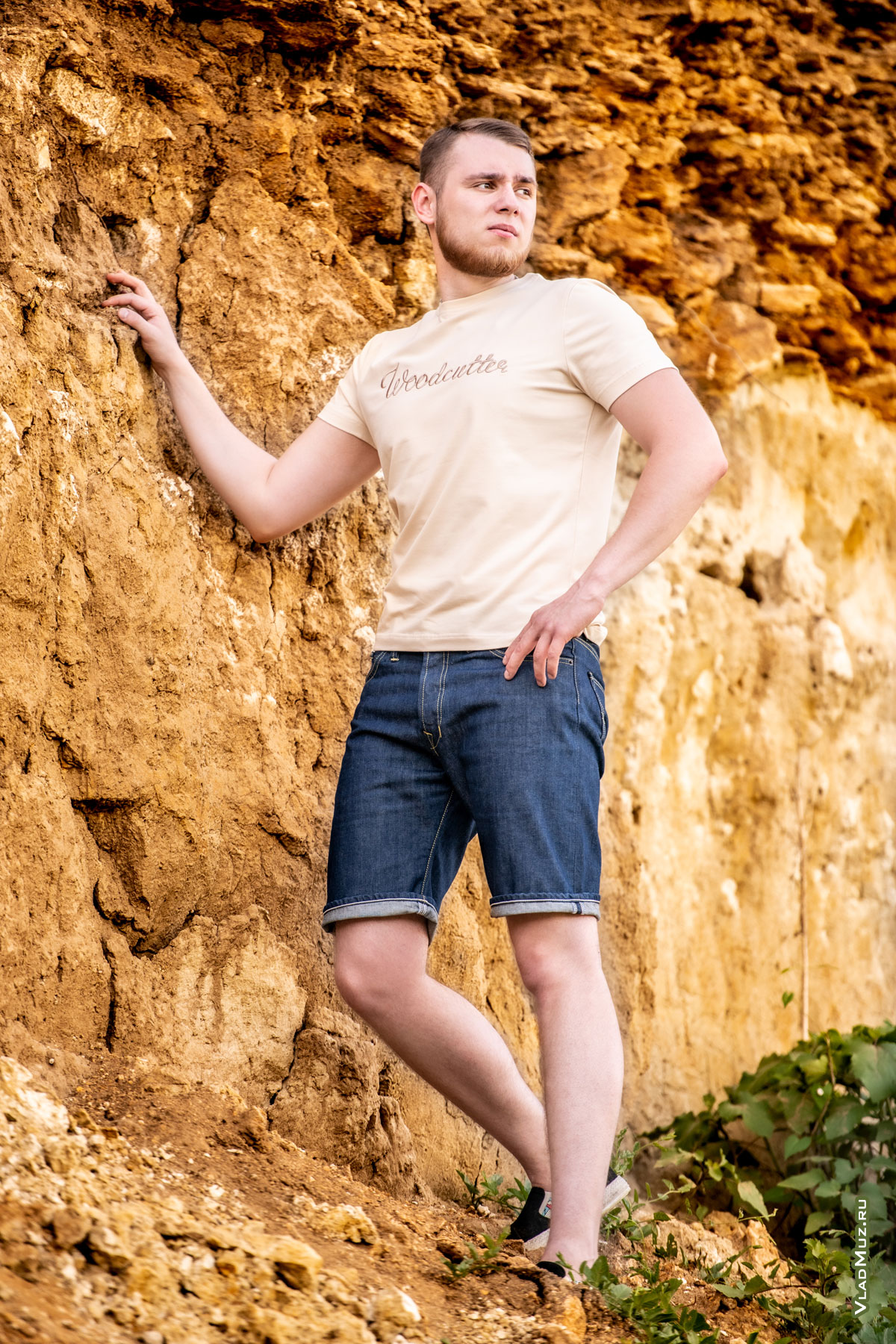 Фото мужчины в полный рост в шортах и светло-бежевой футболке Woodcutter на фоне карьера