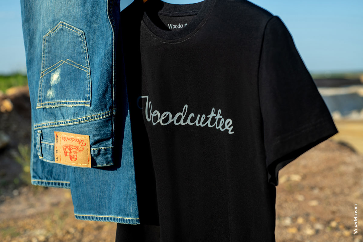 Фото патча на поясе синих джинсов и логотипа Woodcutter на черной футболке крупным планом