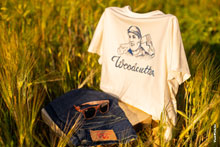 Фото солнцезащитных очков, джинсов и футболки Woodcutter на стуле в ржаном поле