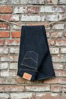 Фото темно-синих джинсовых брюк Woodcutter на фоне грубой кирпичной стены