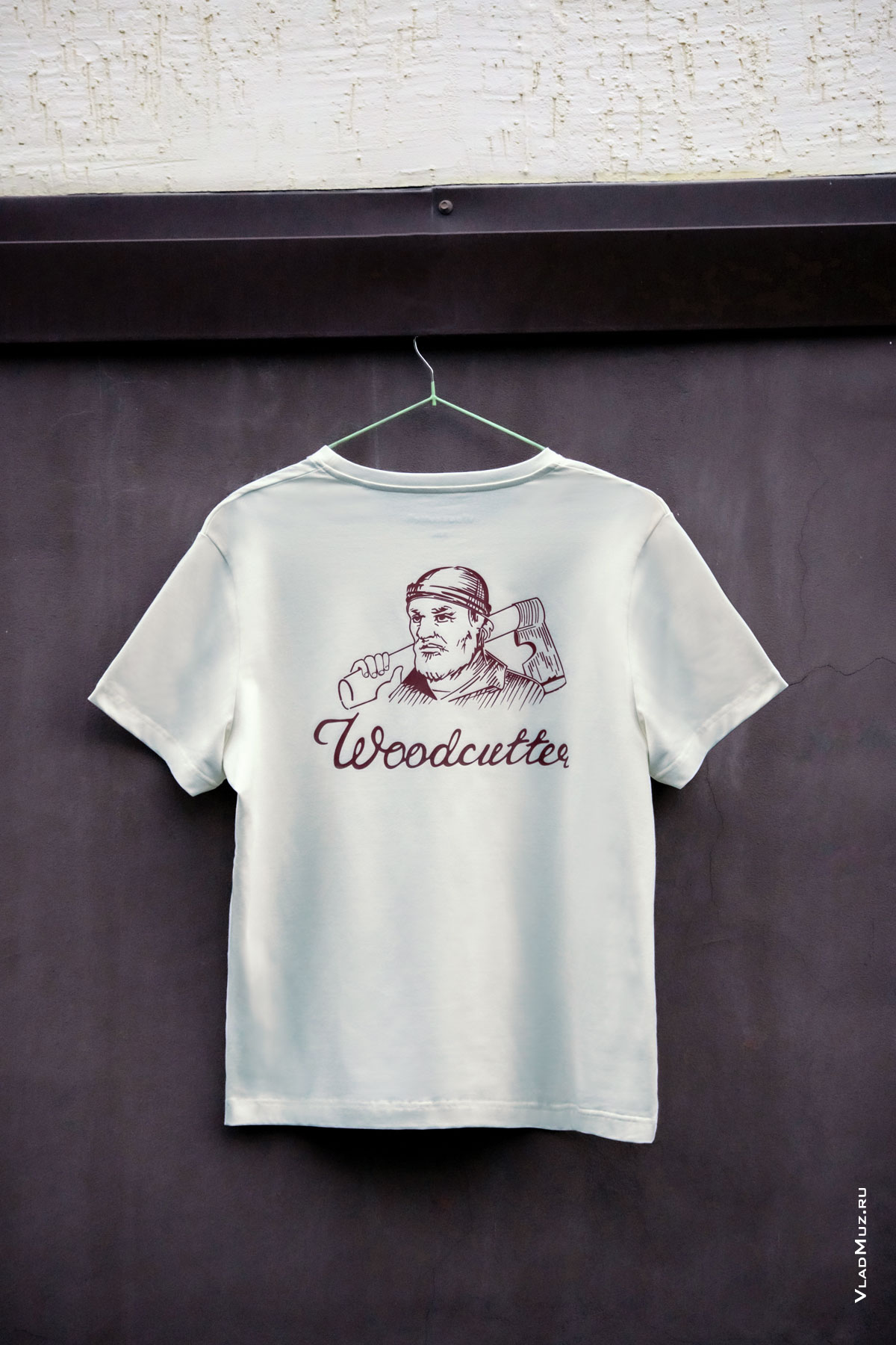 Фото бежевой футболки Woodcutter на фоне коричневой стены