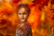 Осеннее фото маленькой девочки в расфокусах красно-желтых листьев