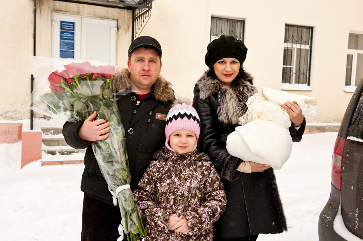 Фото папы, мамы с новорожденным ребенком и дочерью возле роддома в Новочеркасске
