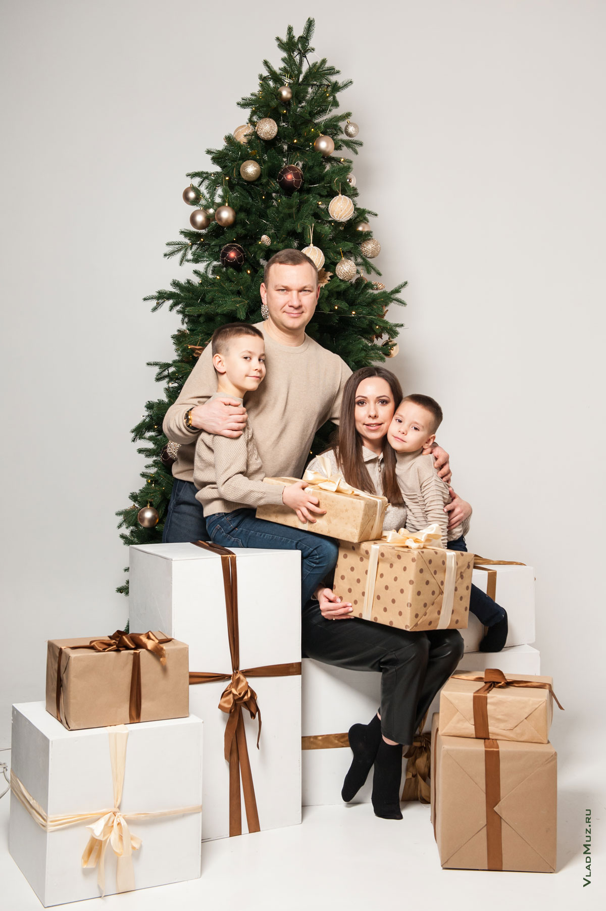 Фото семьи с детьми с подарками у новогодней елки на белом фоне