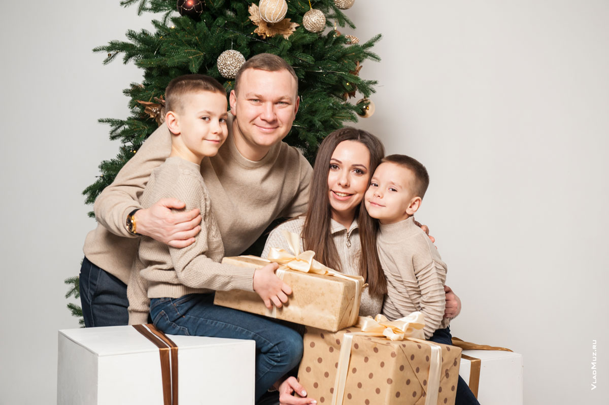 Семейное фото с подарками у новогодней елки на белом фоне