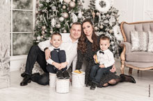 Семейный фотопортрет в студии с 2-мя детьми на фоне новогодних ёлок