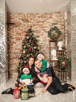 Фото семейной пары с маленькими детьми в студии на фоне елки и новогодних декораций