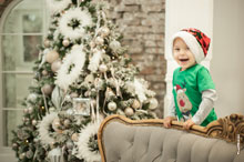 Фото весёлого малыша в студии в новогодней шапке-колпаке на фоне ёлки