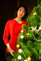 Женский фотопортрет возле новогодней елки в солнечных лучах