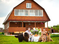 Фото семейной пары с собаками на фоне деревянного дома