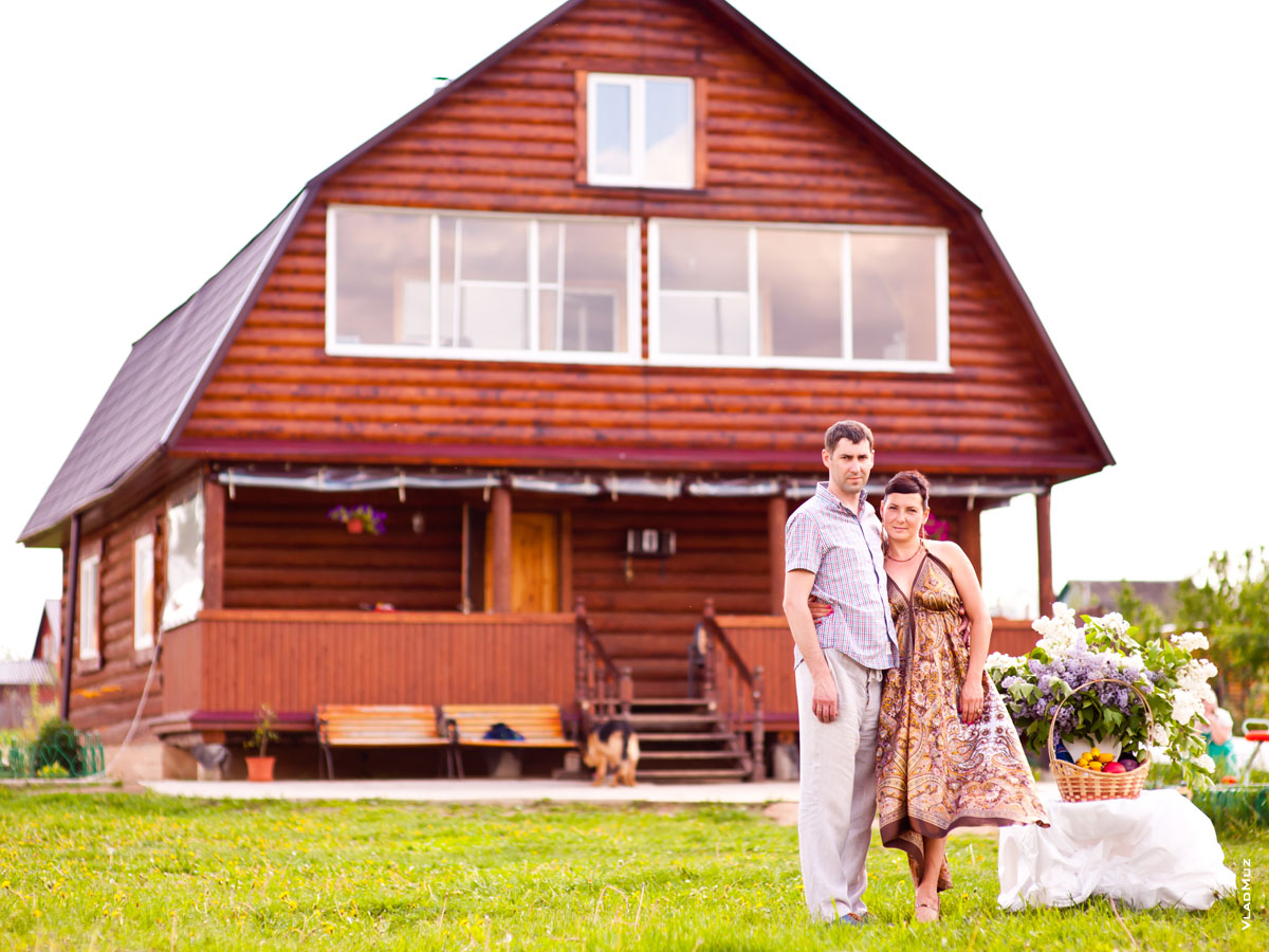 Фото семейной пары, стоящей на фоне загородного дома