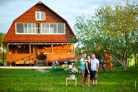 Фото сестры и братьев на лужайке, на фоне деревянного дома