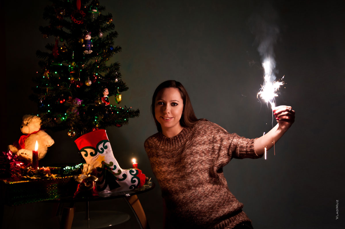 Фото девушки с новогодней елкой, в темноте, при свечах и с бенгальским огнем в руке