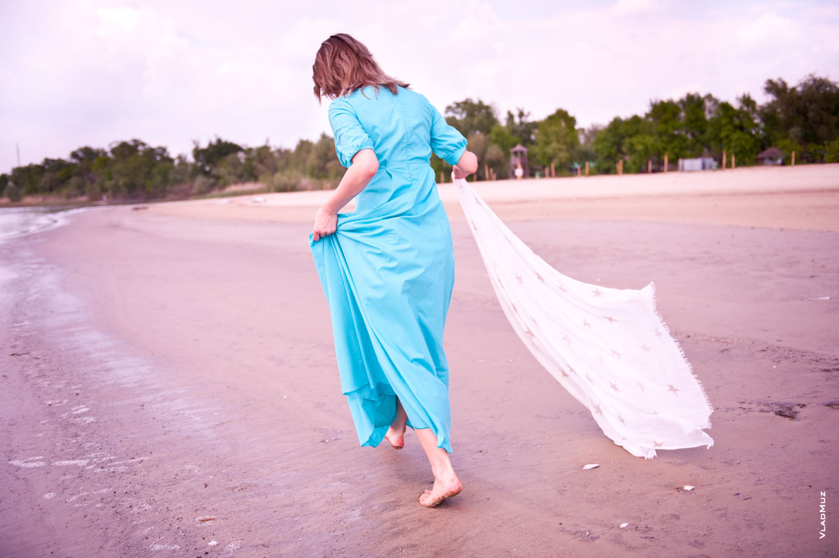 Фото девушки со спины, идущей по песчаному берегу с шалью в руке