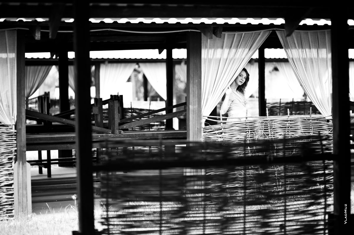 Фото девушки в деревянном шатре, выглядывающей из-за шторы