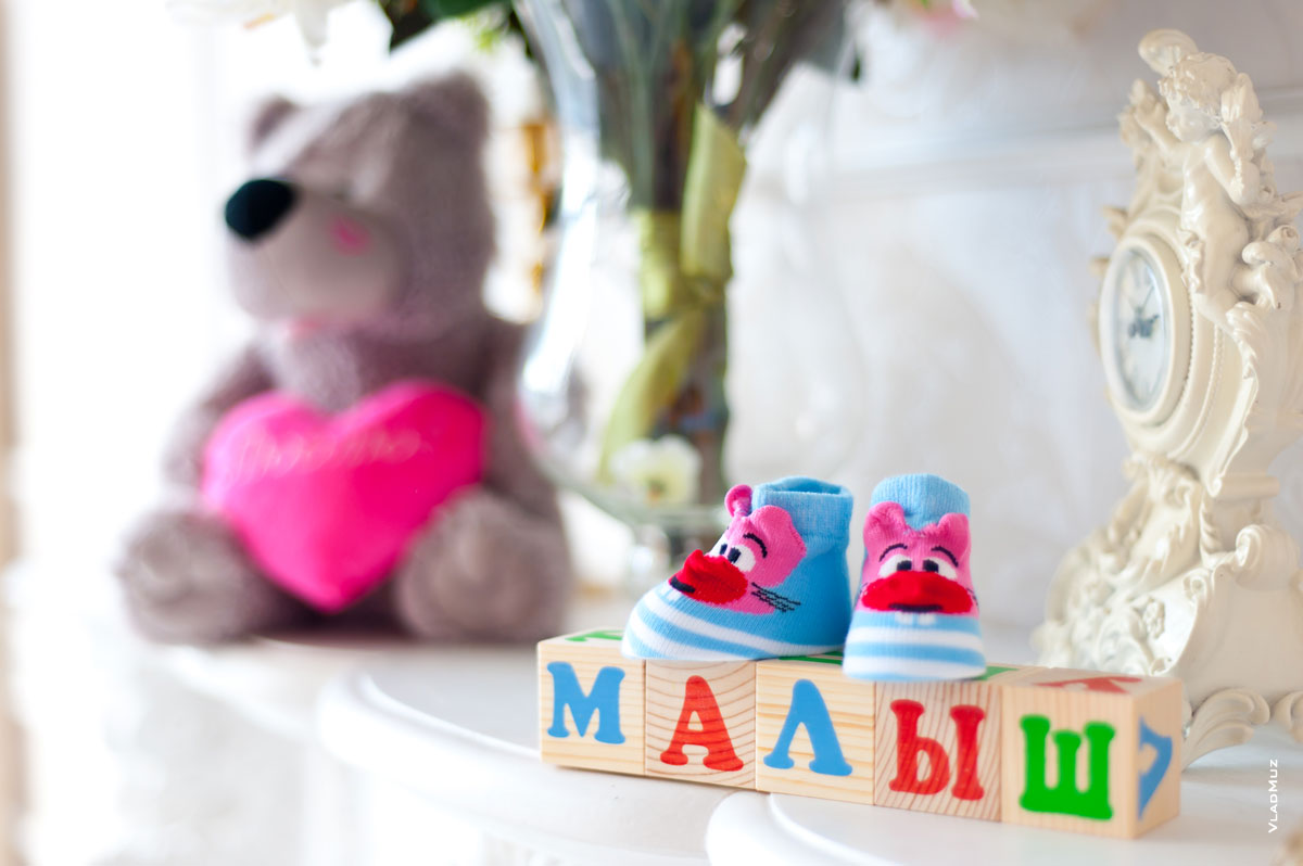 Фотонатюрморт: деревянные кубики, голубые пинетки, мягкая игрушка медведя с розовым сердцем