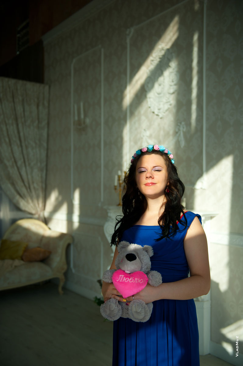 Фото будущей мамы с мягкой игрушкой медведя со словами «Люблю» в лучах солнца
