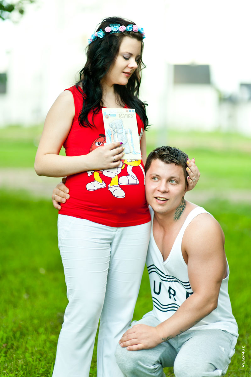 Семейное фото на природе: муж прислушивается к животу беременной жены