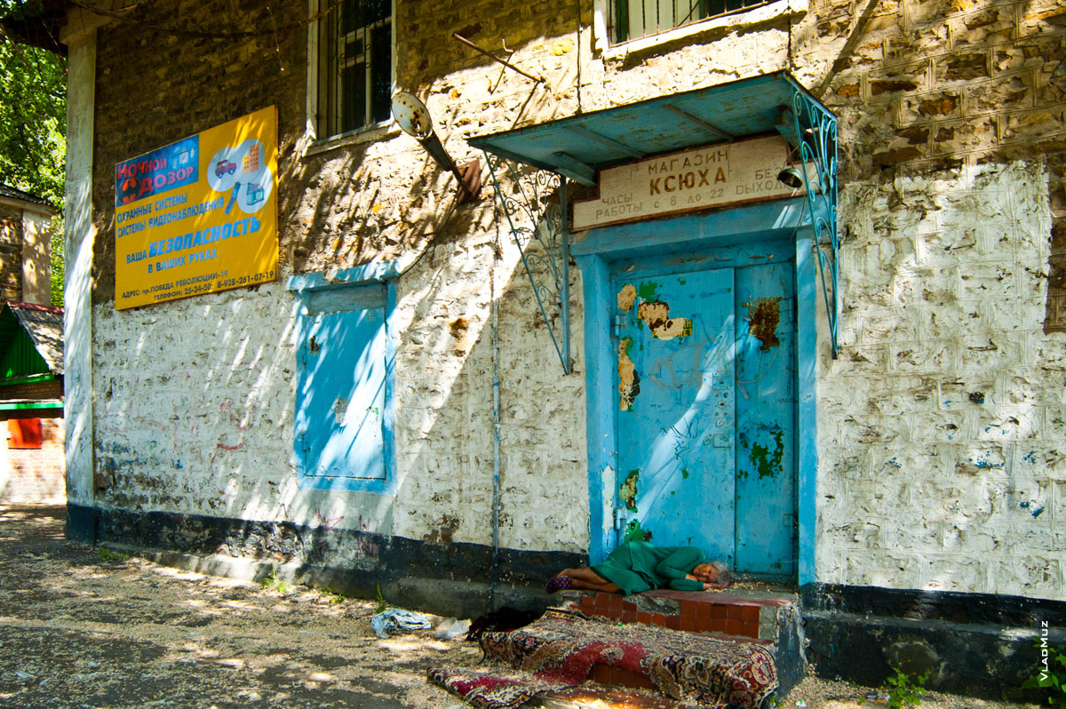 Спящая женщина у старого закрытого магазина в городе Шахты Ростовской области