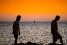 Жанровый фотопейзаж: фото яхты на морском горизонте, после заката солнца, на фоне 2-х силуэтов в расфокусе