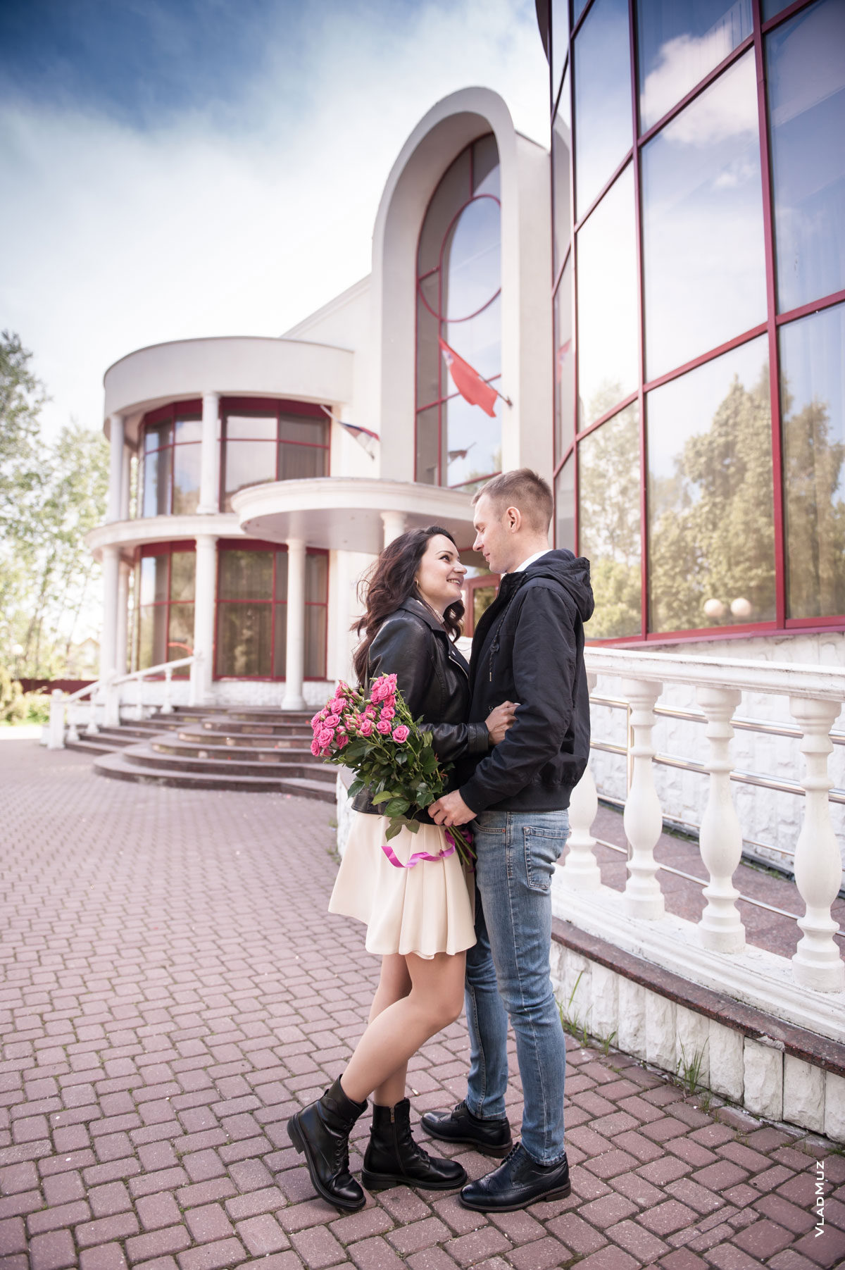 Фото девушки и мужчины с букетом цветов в полный рост на фоне ЗАГСа в г. Железнодорожном в Московской области