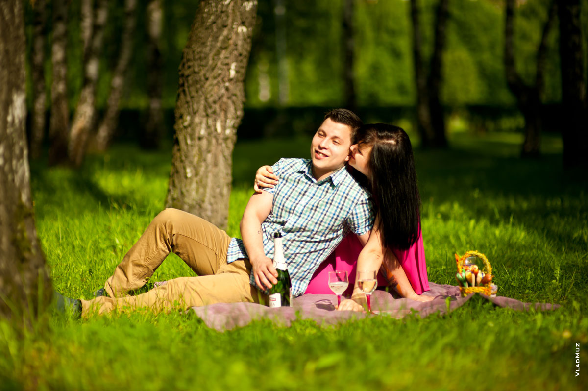 Красивое, яркое цветное фото влюбленной пары на зеленой лужайке в лучах солнца
