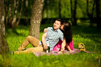 Красивое, яркое цветное фото влюбленной пары на зеленой лужайке в лучах солнца