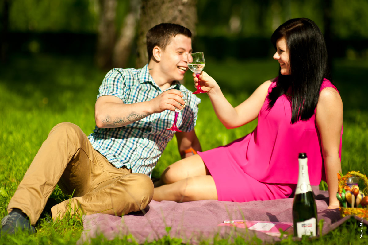 Романтический лайфстайл: влюбленные на лужайке с шампанским смеются