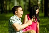 Веселый момент из фотосессии влюбленной пары с шампанским на природе