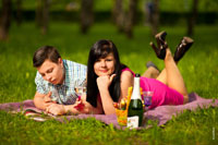 Приятный летний отдых: фото девушки с бокалом шампанского и юноши, лежащих на лужайке
