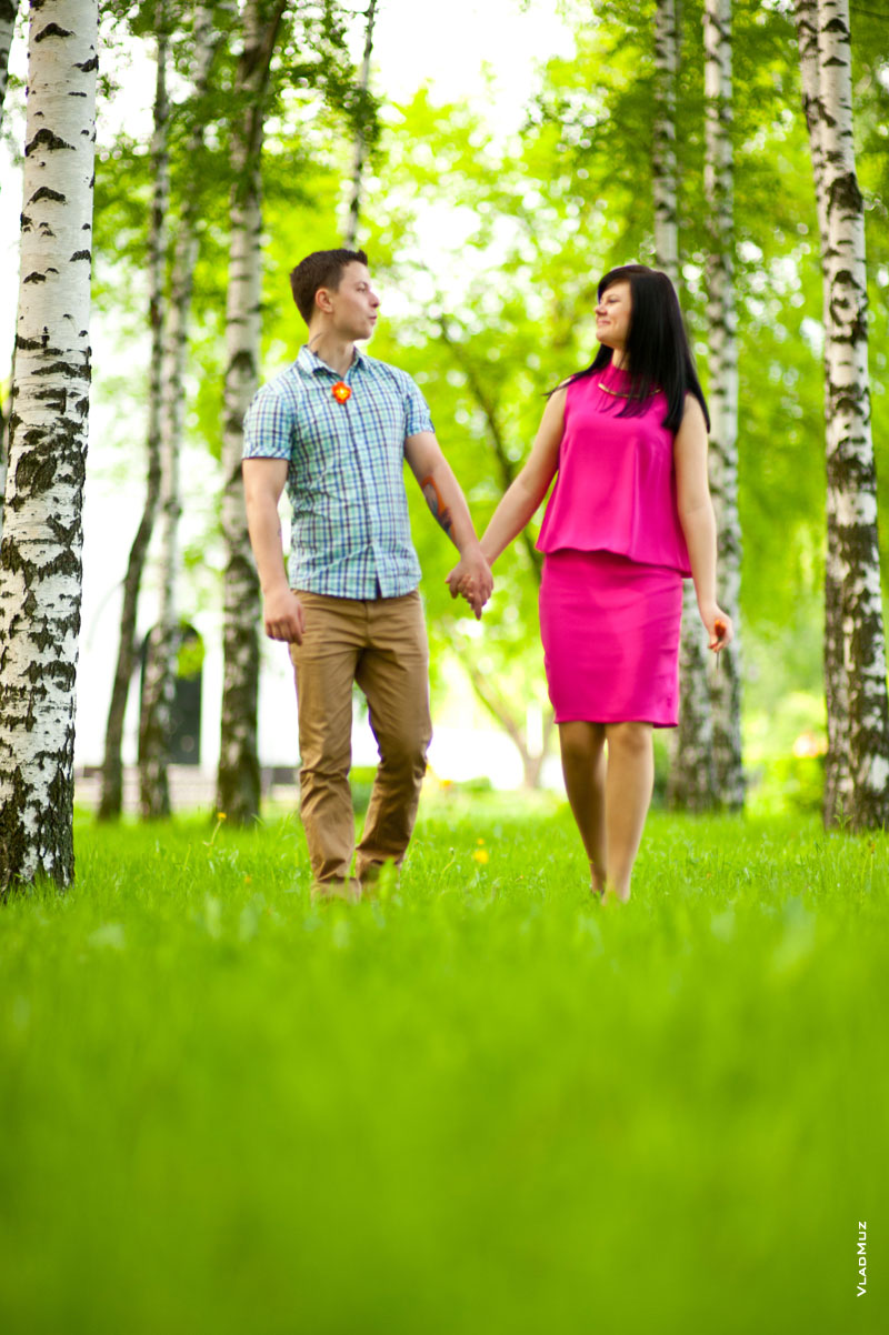 Фото влюбленной пары, гуляющей по зеленой лужайке среди берез