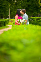 Фото поцелуя влюбленных на фоне зелени клумб и деревьев