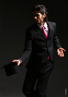 Динамичное фото (в темной тональности) модного мужчины в костюме, с цилиндром в руке