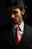 Модный фотопортрет модели-мужчины в костюме с галстуком в темной тональности, крупный лицевой план