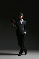 Фото мужчины-модели в темной тональности (на темном фоне) в полный рост с цилиндром в руке