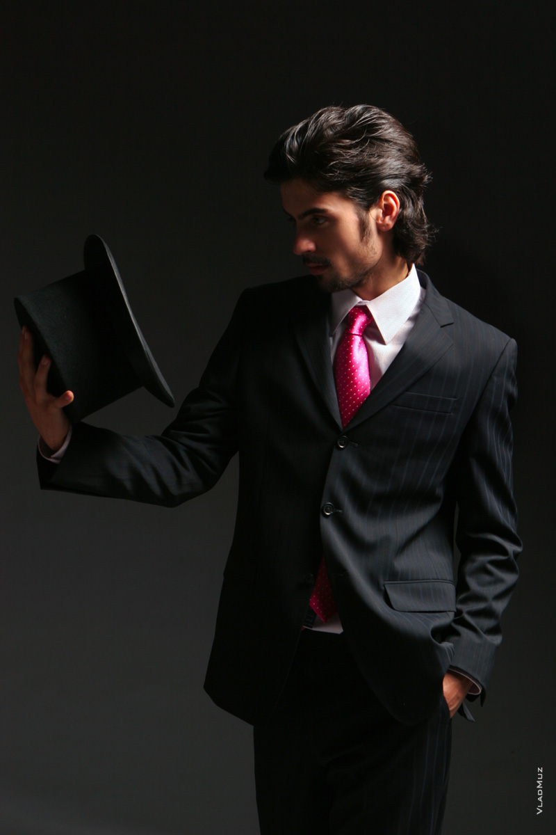 Мужчина, профессиональная модель, в студии, в костюме с галстуком, с цилиндром в руке