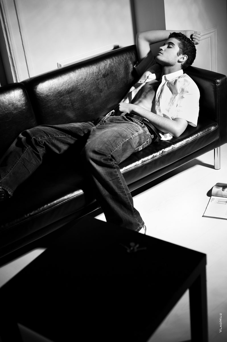 Черно-белое фото мужчины в рубашке и джинсах, спящего на диване
