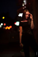 Фото девушки с рукой у лица, стоящей на фоне ночного города