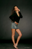 Еще одно фото девушки-модели в полный рост в джинсовой юбке на темном фоне
