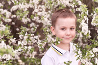 Фото мальчика на весеннем пленэре, на фоне цветущего дерева