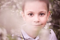 Детский весенний фотопортрет в цветущем саду с избирательной резкостью на глазах