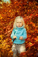 Осеннее фото малыша с улыбкой на красном фоне из листвы