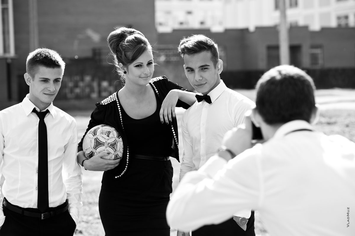Модный жанровый фотопортрет двух юношей с девушкой, держащей футбольный мяч в руках