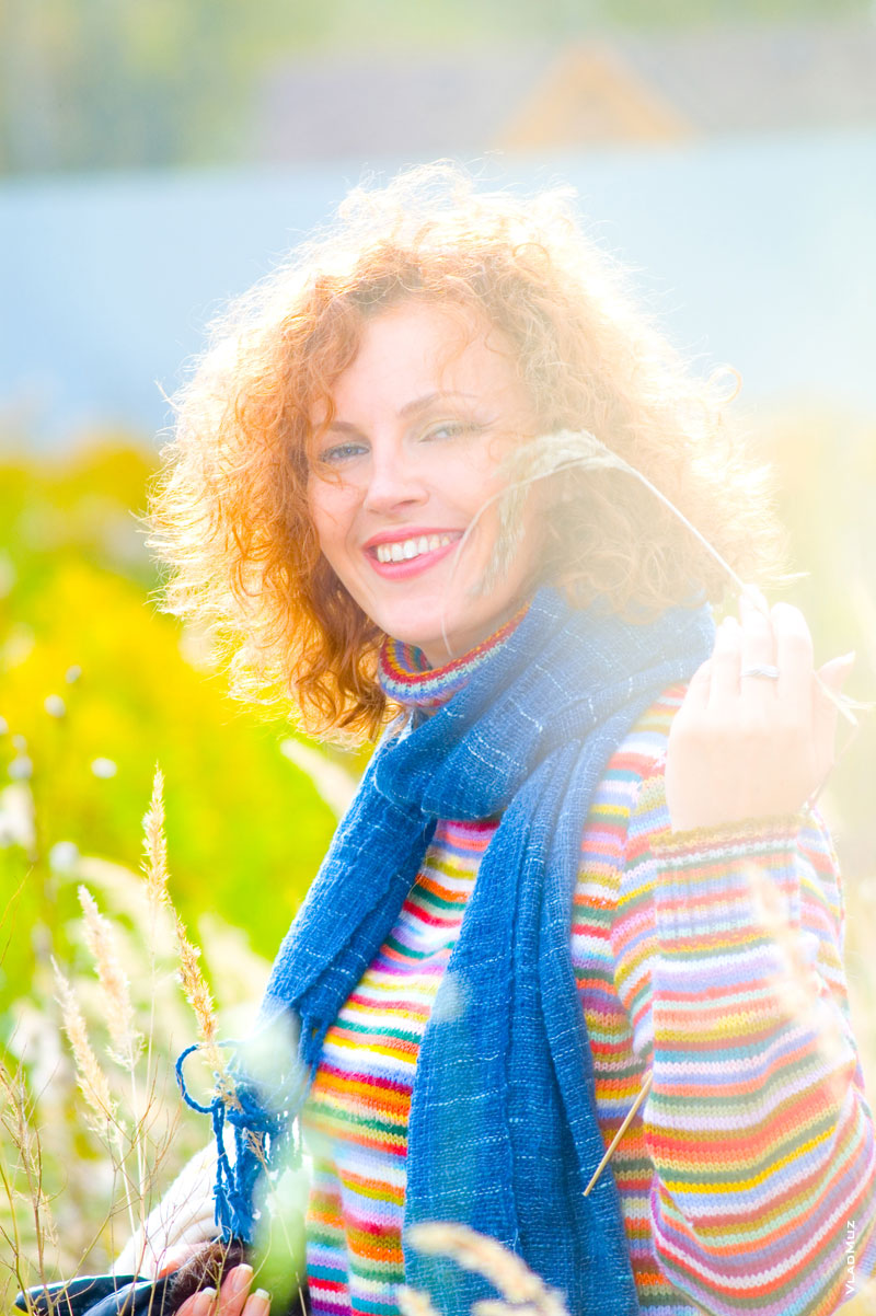 Эмоциональный фотопортрет девушки с улыбкой в ярком цветном свитере в контровом солнечном свете на осеннем пленэре