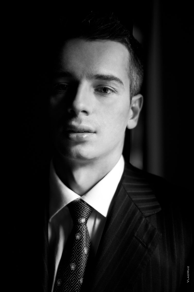 Черно-белый мужской фотопортрет в костюме в студии, с естественным светом из окна