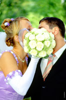 Невеста закрывает поцелуи с женихом своим букетом